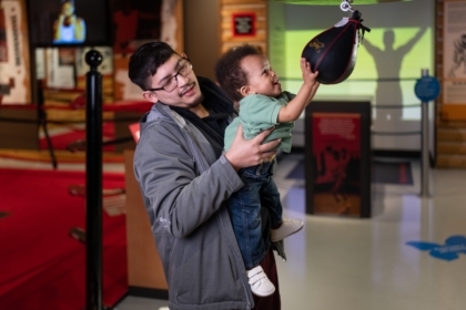Father and toddler child in the Deer Lake exhibit playing with a speed bag