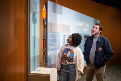 Two people looking at an Olympic torch in an exhibit