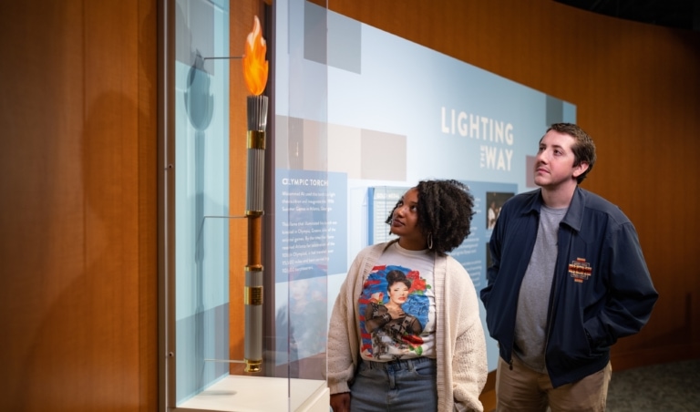 Two people looking at an Olympic torch in an exhibit