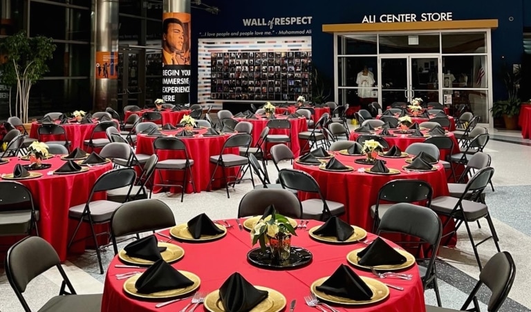 Lobby of Muhammad Ali Center set up for an event with red round tables and black chairs