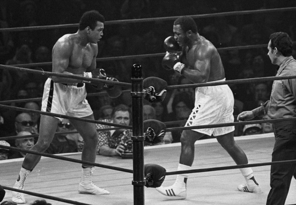 Black and white photo of Muhammad Ali and Joe Frazier inside boxing ring