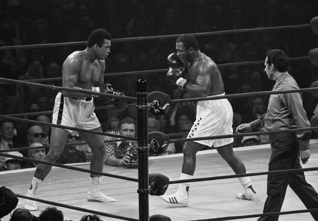 Black and white photo of Muhammad Ali and Joe Frazier inside boxing ring
