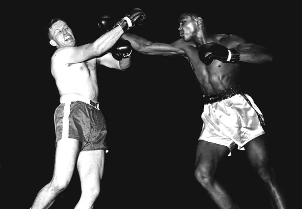 Black and white photo of Ali throwing punch at Hunsaker