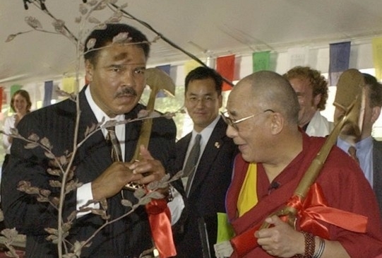 Color photo of Muhammad Ali standing with the Dalai Lama