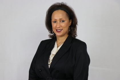 Portrait photo of a woman in a black business jacket and beige top