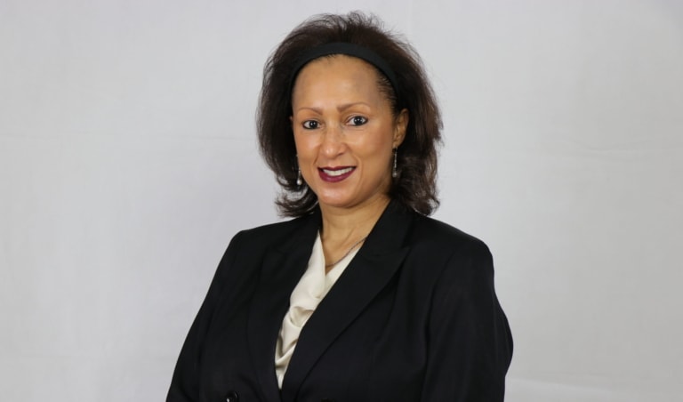 Portrait photo of a woman in a black business jacket and beige top