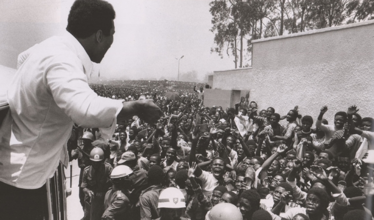 Black and white photo of Muhammad Ali in front of a huge crowd of people in Zaire