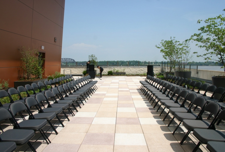 Two long rows of folding chairs on either side of a central walkway on an outdoor patio