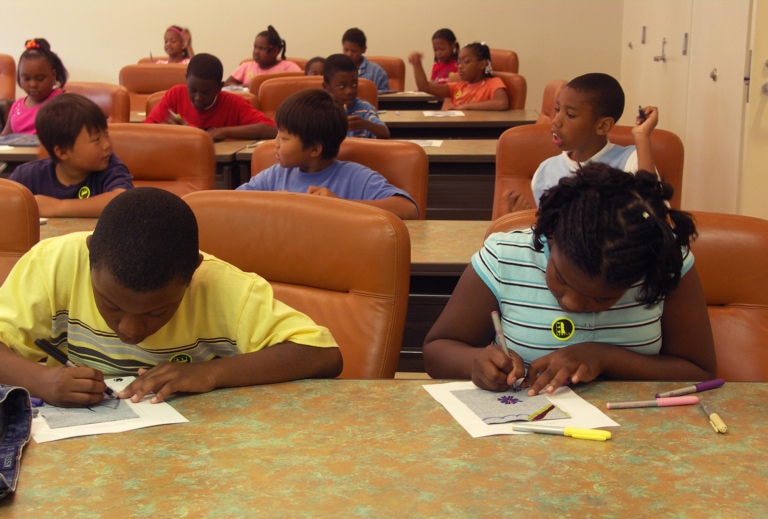 A class of students drawing on worksheets with colored markers