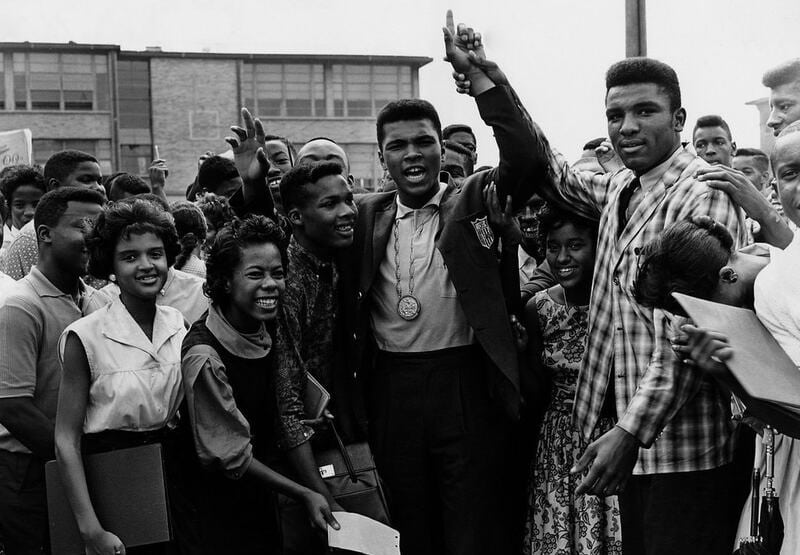 Black and white photo of Muhammad Ali with group at Central High School
