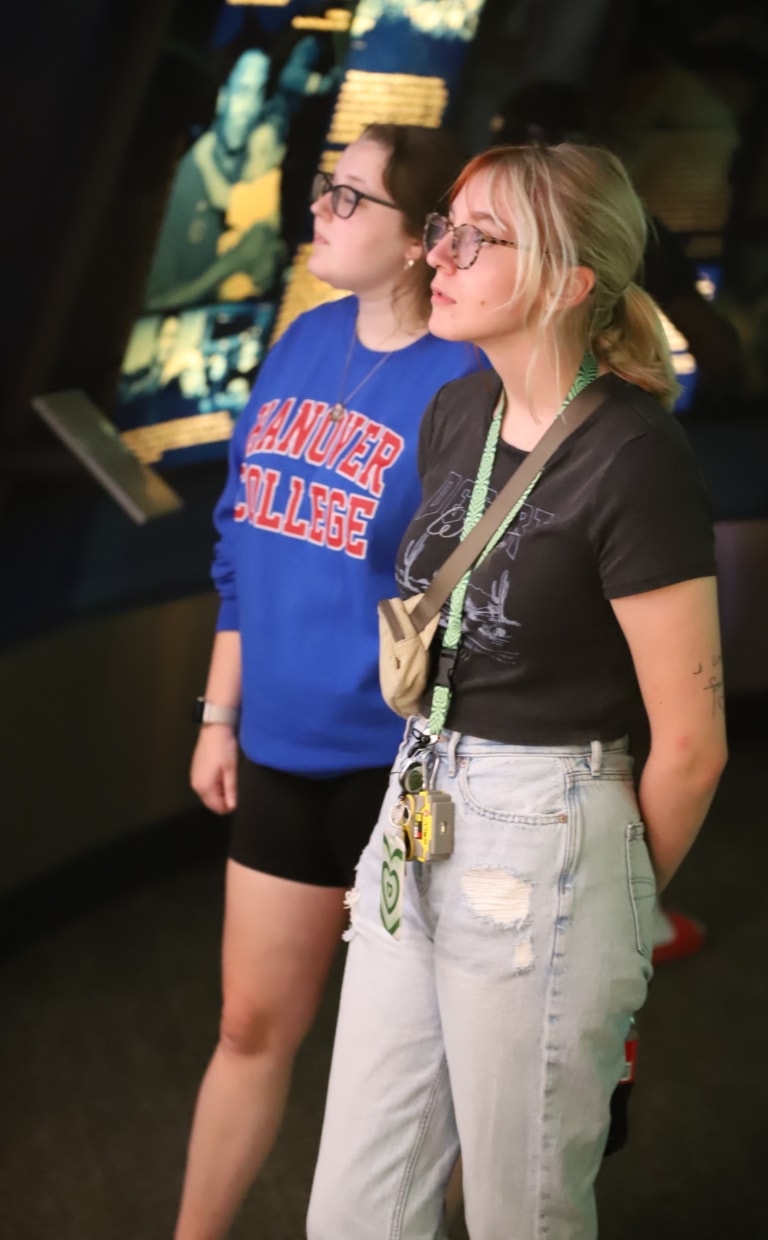 Two people with glasses, one with a Hanover College sweatshirt, looking at a museum display
