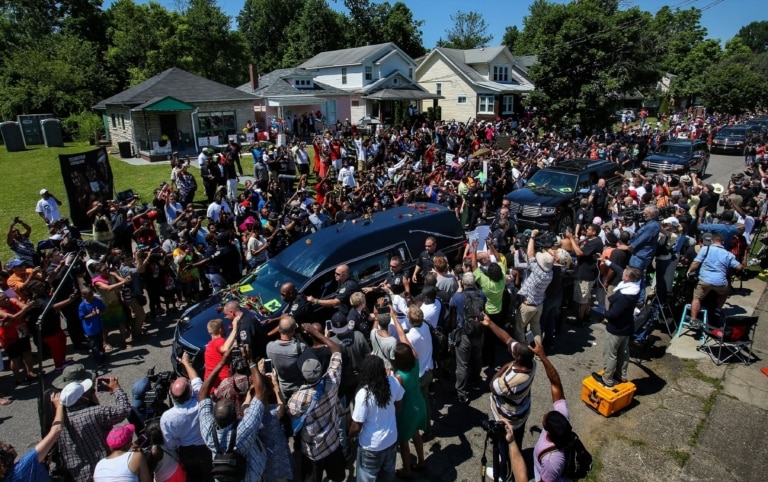Funeral procession surrounded by a crowd drives past Muhammad Ali's boyhood home