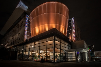 Exterior of Muhammad Ali Center with a large curving copper element of the architecture illuminuated