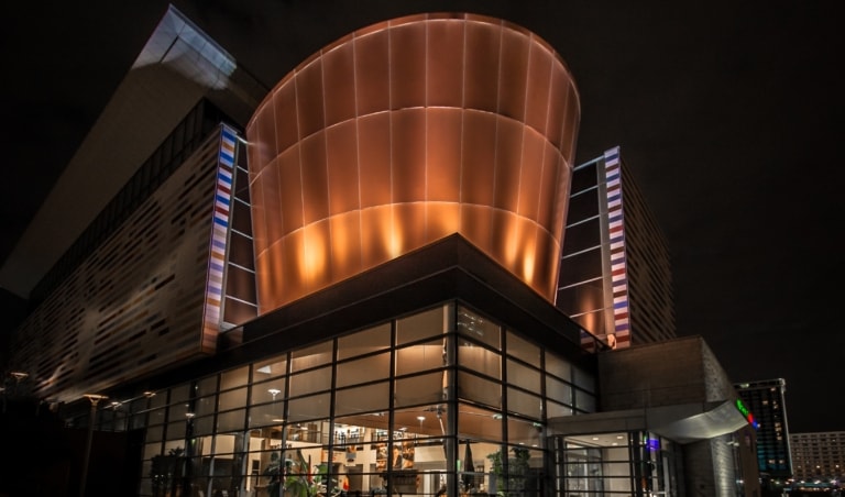 Exterior of Muhammad Ali Center with a large curving copper element of the architecture illuminuated