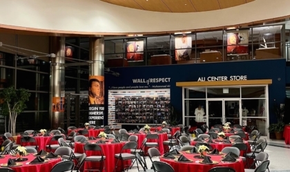Lobby of Muhammad Ali Center set up for an event with red round tables and black chairs