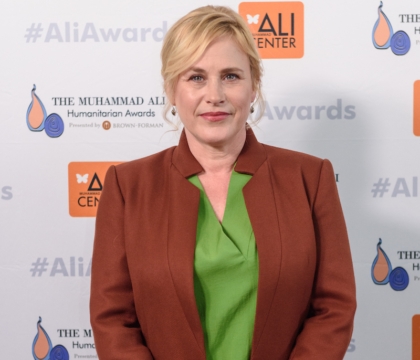 Patricia Arquette, wearing burgundy coat and green blouse, poses for camera