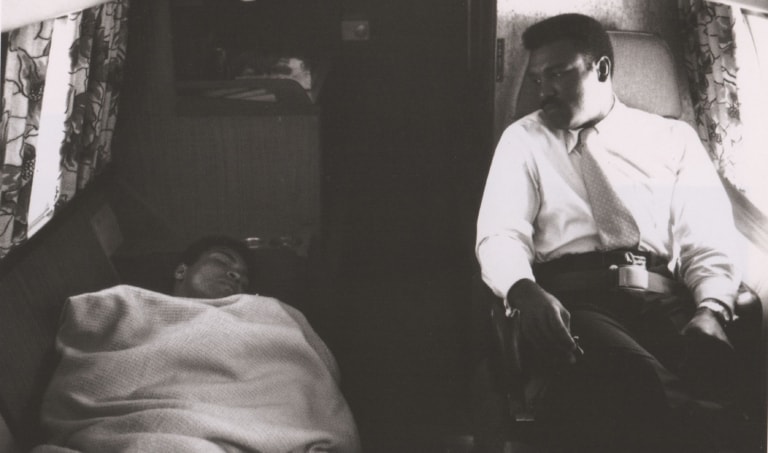 Black and white photo of Muhammad Ali sleeping as his brother Rahman watches
