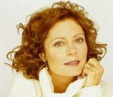 Susan Sarandon, wearing white sweater, poses for camera with fist near her chin