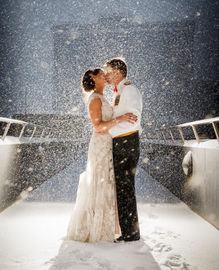A couple kissing on a walkway in the snow