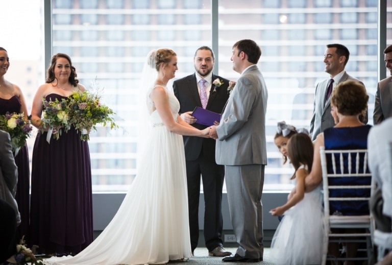 Wedding ceremony with bride and room holding hands in front of an officiant