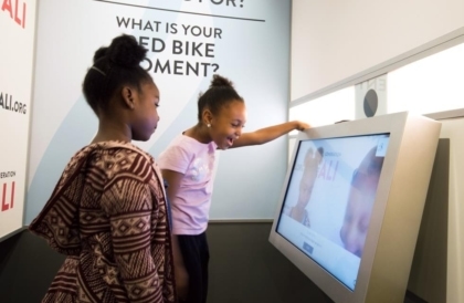 Two girls in front of a large touchscreen interactive in an exhibit