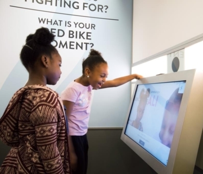 Two girls in front of a large touchscreen interactive in an exhibit