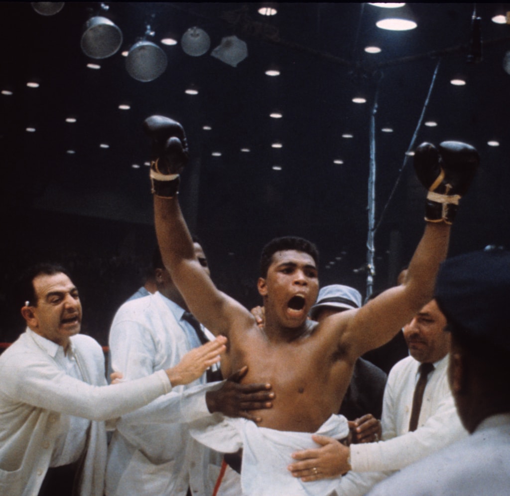 Color photo of Muhammad Ali celebrating win with fists in the air