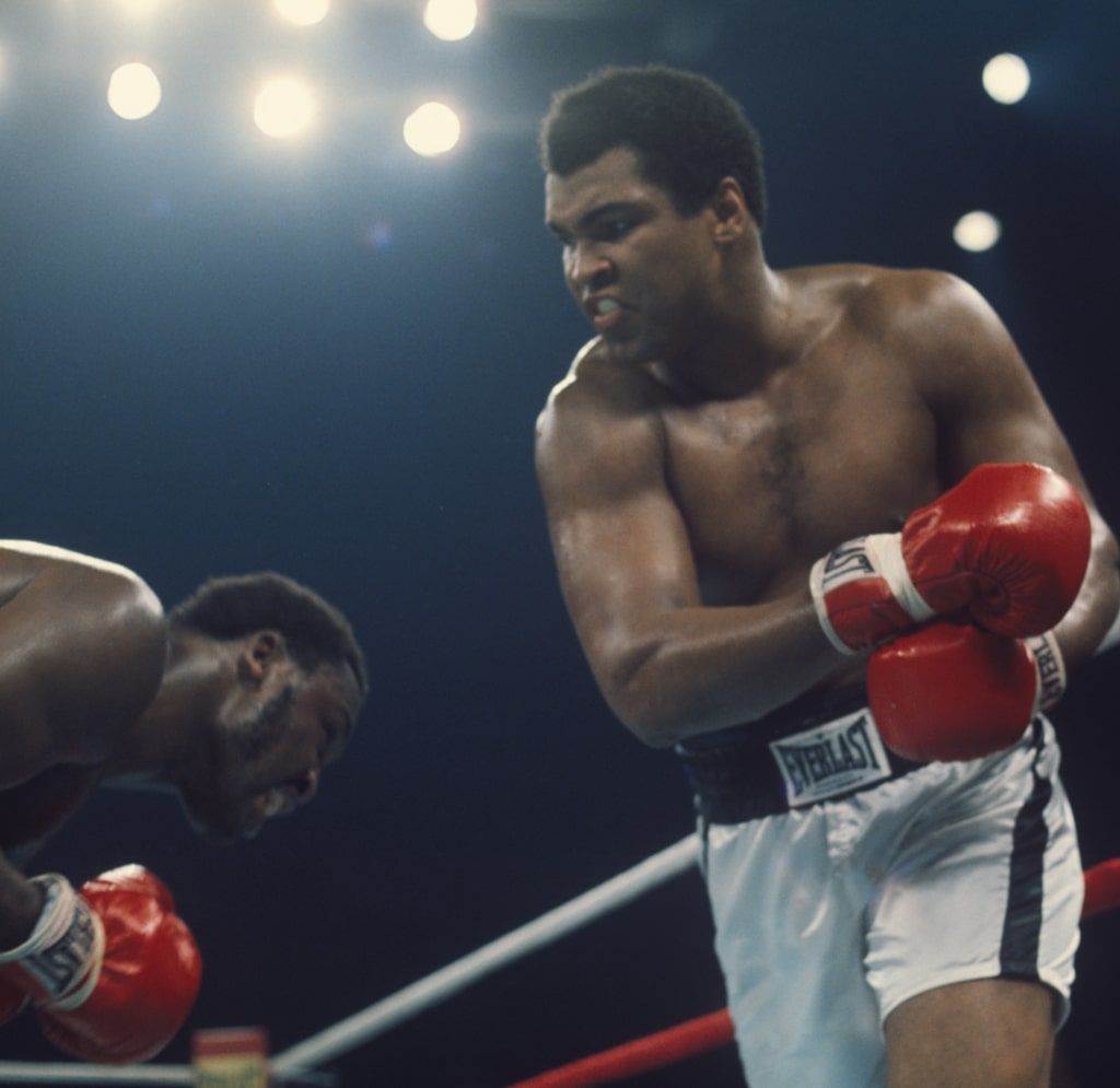 Action photo of Muhammad Ali and Joe Frazier in the ring as Frazier dodges punch