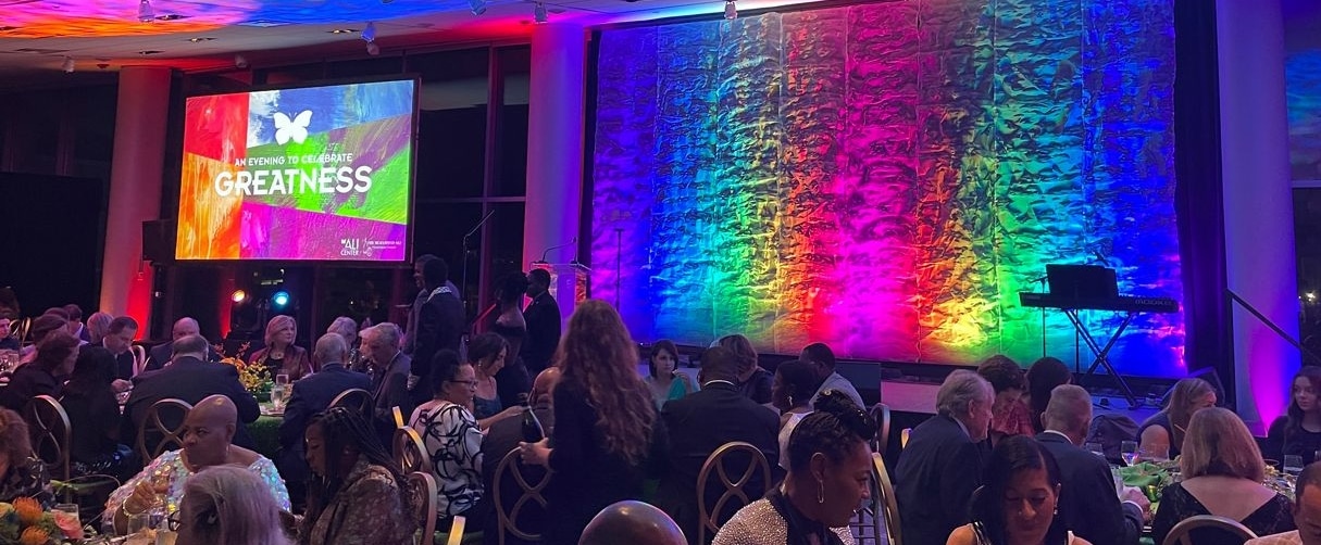 Ballroom full of people attending an event and a colorful empty stage