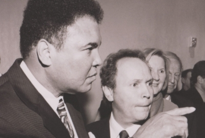 Black and white photo of Muhammad Ali standing next to Billy Crystal and pointing