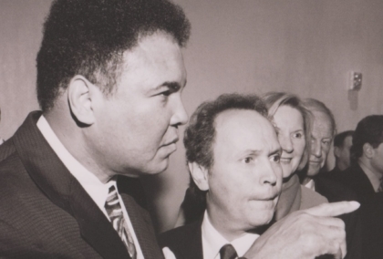 Black and white photo of Muhammad Ali standing next to Billy Crystal and pointing