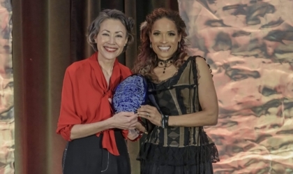 Two women posing for camera while holding an award