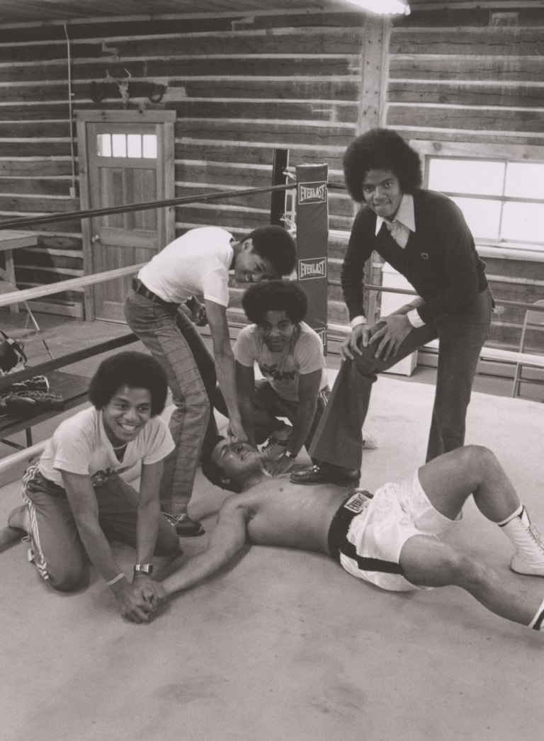 Black and white photo of the Jacksons and Muhammad Ali in a boxing ring