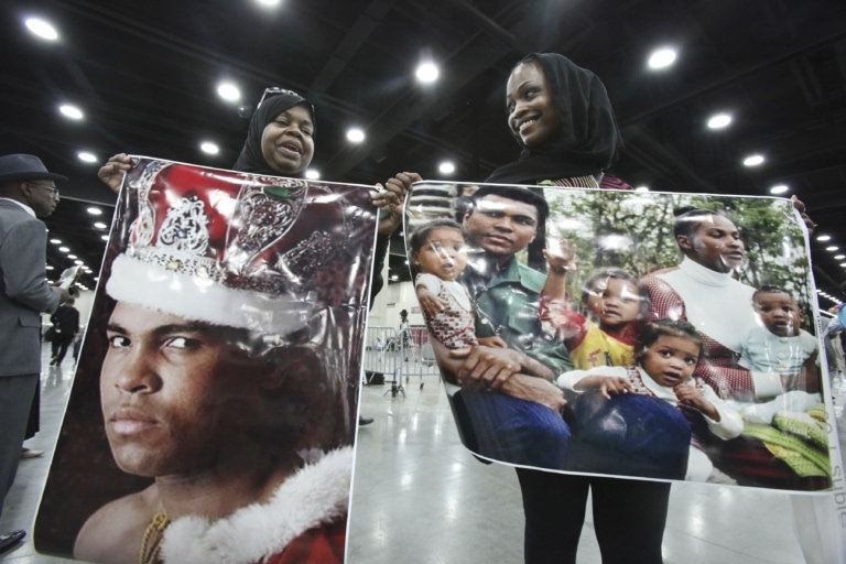 Women hold large photos of Muhammad Ali and family