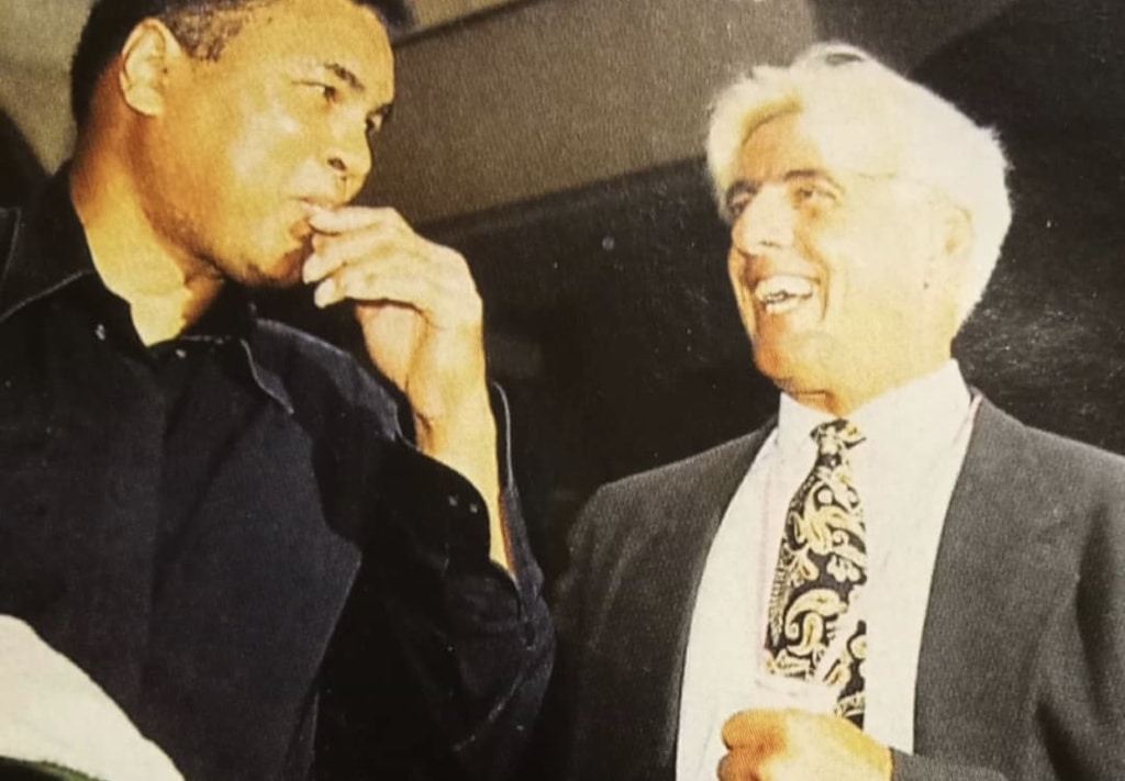 Muhammad Ali and Ric Flair facing each other, Flair is smiling