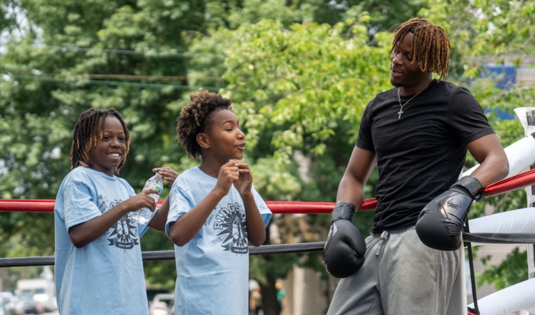 Two kids in boxing ring learning with mentor
