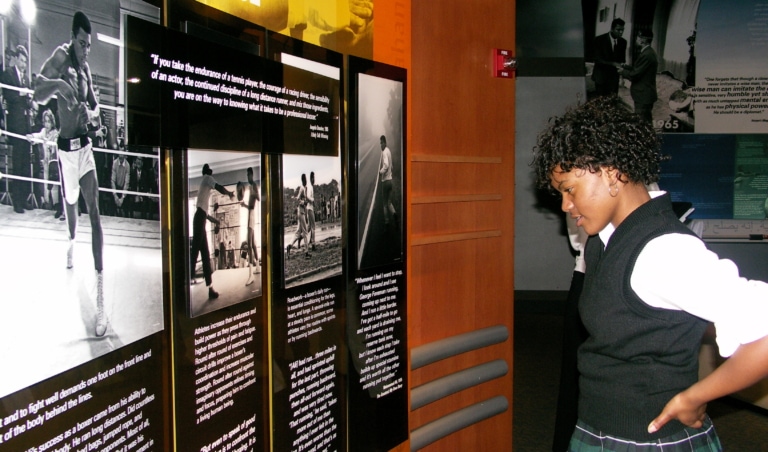 Student reading museum exhibit about Muhammad Ali