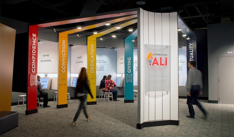 Museum guests sitting in Generation Ali booths while others walk by