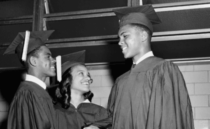 Muhammad Ali in graduation cap and gown shaking hands with students