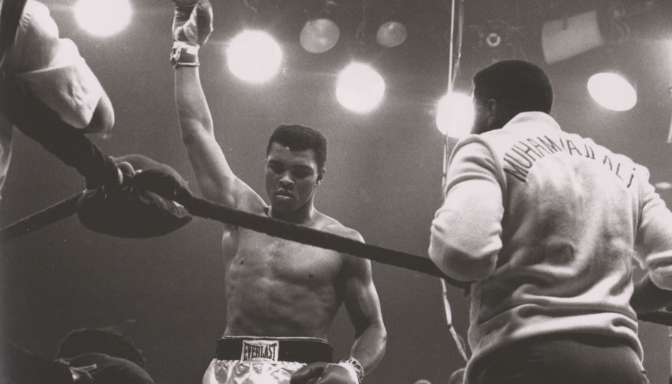 Black and white photo of Muhammad Ali in a boxing ring victorious
