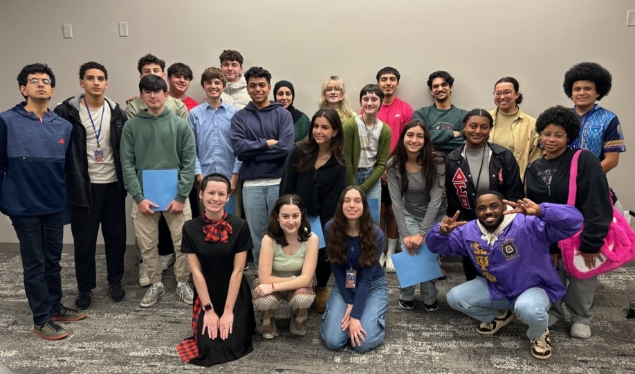 Group of students standing by wall posing for camera