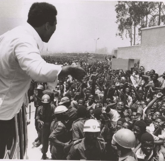 Black and white photo of Muhammad Ali in front of a huge crowd of people in Zaire