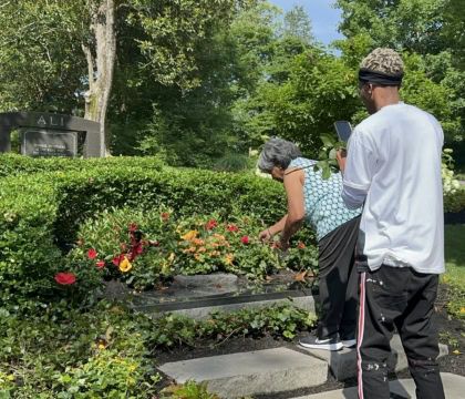 Photo of man and woman placing rose on Muhammad Ali's gravesite