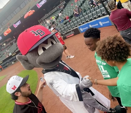 Louisville Bats mascot dressed in Muhammad Ali robe greeting kids on baseball field
