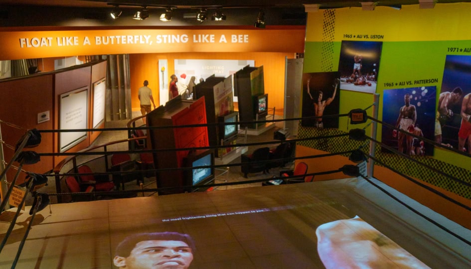 Photo of boxing ring with people walking around observing exhibits