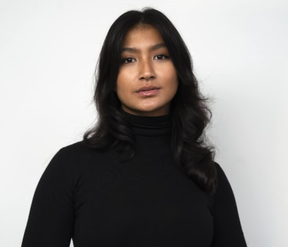 Photo of woman with medium-length dark hair wearing black sweater looking at camera