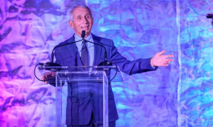 Dr. Fauci in a suit speaking at a lectern