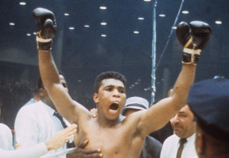 Photo of Muhammad Ali celebrating with gloves in the air