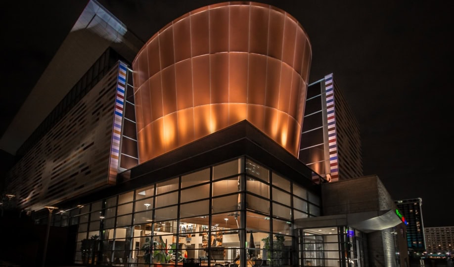 Exterior of Muhammad Ali Center with a large curving copper element of the architecture illuminuated