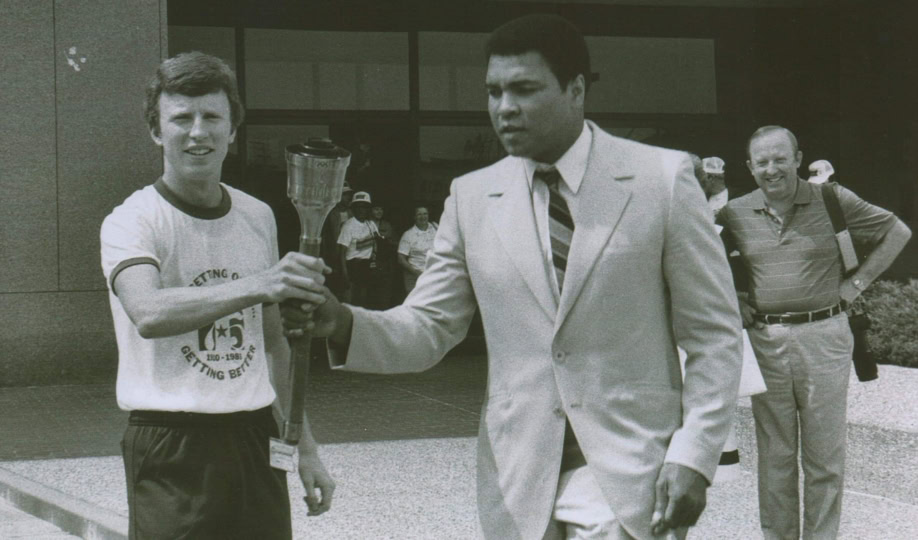 Picture of Muhammad Ali in suit carrying Olympic torch